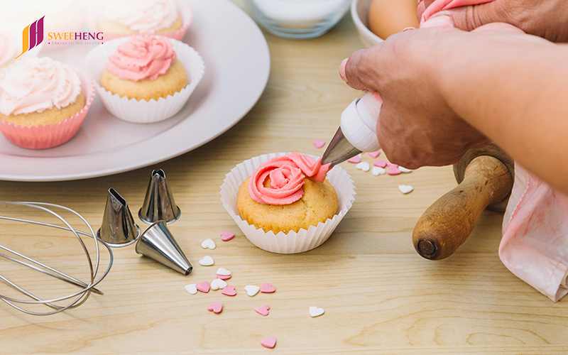 Baker putting frosting:icing on cupcakes:cookies